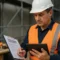 Australian tradesperson reviewing trade licence documents with digital tablet at construction site in 2025